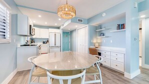 A modern kitchen with white cabinets, a round marble table, and a chandelier.