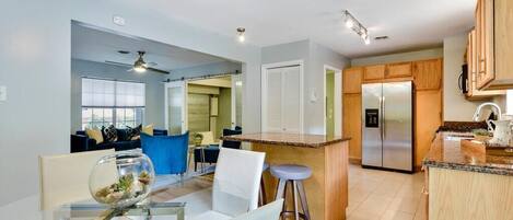 A modern kitchen with a central island, wooden cabinets, and a stainless steel refrigerator.