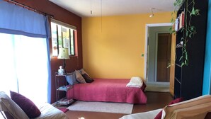 Una habitació amb un llit, dues cadires, una làmpada i una biblioteca.