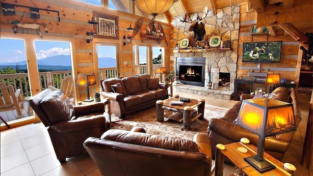 A cozy log cabin interior with a fireplace, leather furniture, and a scenic mountain view. - Mtn Views-4BR-GameRm-More! (Sevierville)