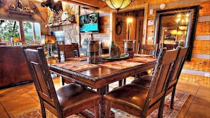 A wooden dining table with chairs, a television, and decorative items. - Mtn Views-4BR-GameRm-More! (Sevierville)
