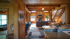 L’intérieur d’une cabane en rondins, avec une cheminée en pierre, des murs en bois, un coin repas et un bar.