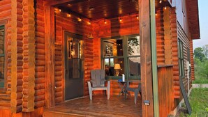 Une cabane en rondins avec une véranda, une chaise et une table.