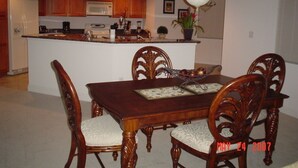Un comedor con una mesa y sillas de madera, una cocina al fondo y un candelabro.