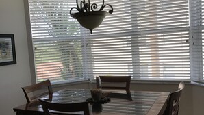 Un comedor con una mesa y sillas, una lámpara colgante y una ventana con persianas.