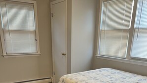 Un dormitorio con suelo de madera, una cama con colcha floral y una puerta blanca.