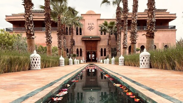 A hotel entrance with a central water feature, palm trees, and traditional architecture. - Exclusive luxury villa (Marrakesh)