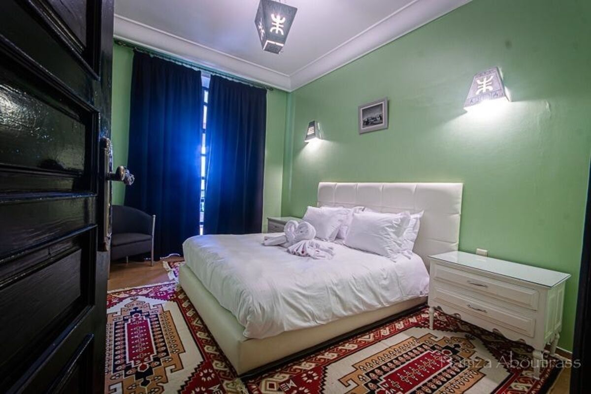 Une chambre à coucher avec un lit, une table de chevet, une chaise et un tapis à motifs.