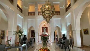 A spacious lobby with a central floral arrangement, high ceilings, and a chandelier. - Exclusive luxury villa (Marrakesh)