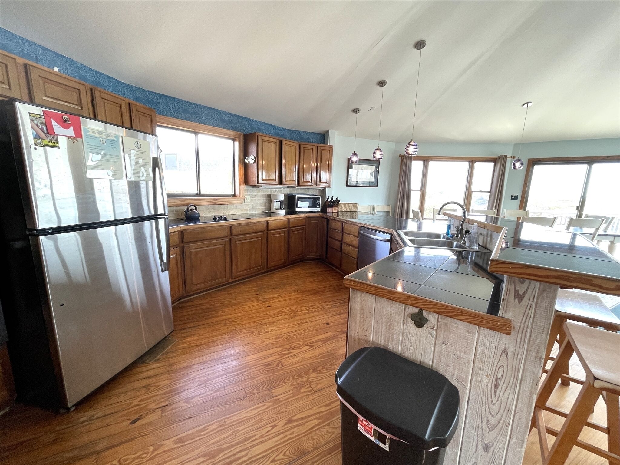 A kitchen with wooden cabinets, a refrigerator, a microwave, and a sink.