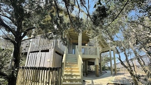 Eine Holzterrasse mit einer Treppe, die zu einer rustikalen Holzhütte inmitten von Bäumen führt.