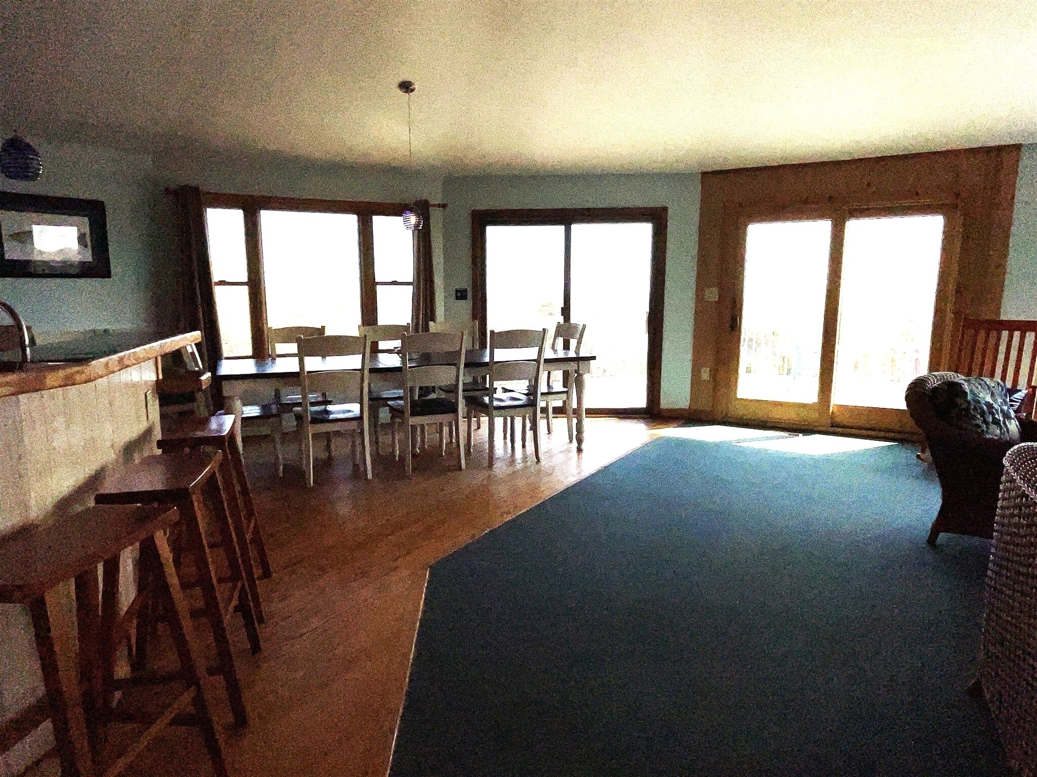 A dining area with a table and chairs, a kitchen counter, and large windows.