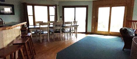 A dining area with a table and chairs, a kitchen counter, and large windows.