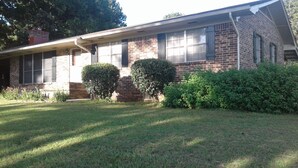 A two-story brick house with a front porch, a small front yard, and two well-maintained bushes. - Comfort and Chickens (Clarksville)