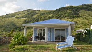 A covered outdoor seating area with a pool table, chairs, and a lounge chair.