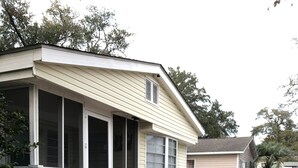 A house with a wooden deck, a covered porch, and a small patio area with outdoor furniture.