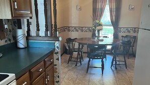 A kitchen with wooden cabinets, a dining table with chairs, a chandelier, and a refrigerator.