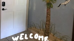A door with a 'WELCOME' sign and a palm tree decoration.