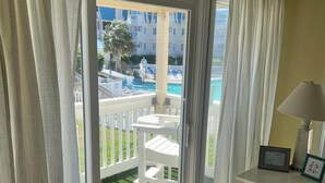 A room with a view of a pool, a white chair, a small table with a lamp, and a sign reading 'BEACH HOUSE'. - Perfectly pool side at APATB! King, Full, 2 Twins (Atlantic Beach)