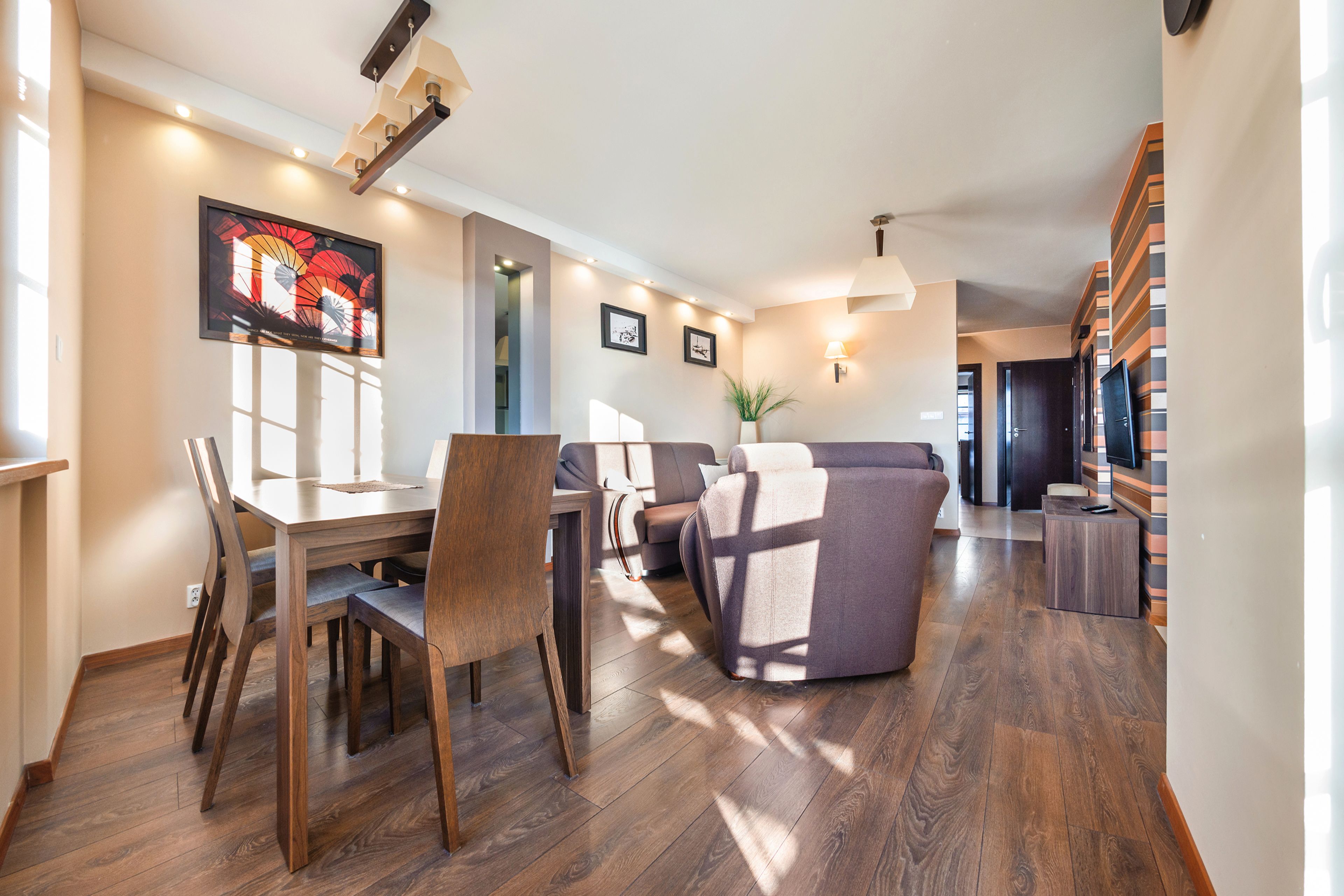 A spacious living area with a dining table, chairs, a sofa, and a TV.
