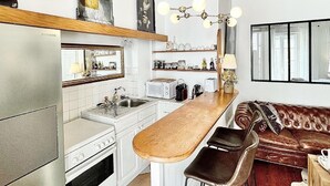 Una cocina con techo de madera, una barra y un rincón de estar con sofá y sillones.