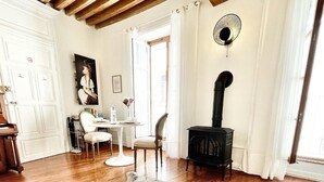 Una habitación acogedora con piso de madera, una mesa de comedor con sillas, una estufa negra y un cuadro en la pared.