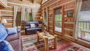 A cozy cabin interior with a wooden ceiling, a leather sofa, a wooden coffee table, and a patterned rug. - View-topia! VIEWS, VIEWS AND MORE VIEWS (Sevierville)