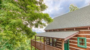 A rustic cabin with a wooden deck and a covered porch, surrounded by lush greenery. - View-topia! VIEWS, VIEWS AND MORE VIEWS (Sevierville)
