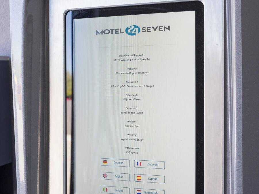 A self-service kiosk with a screen displaying language options for a motel.