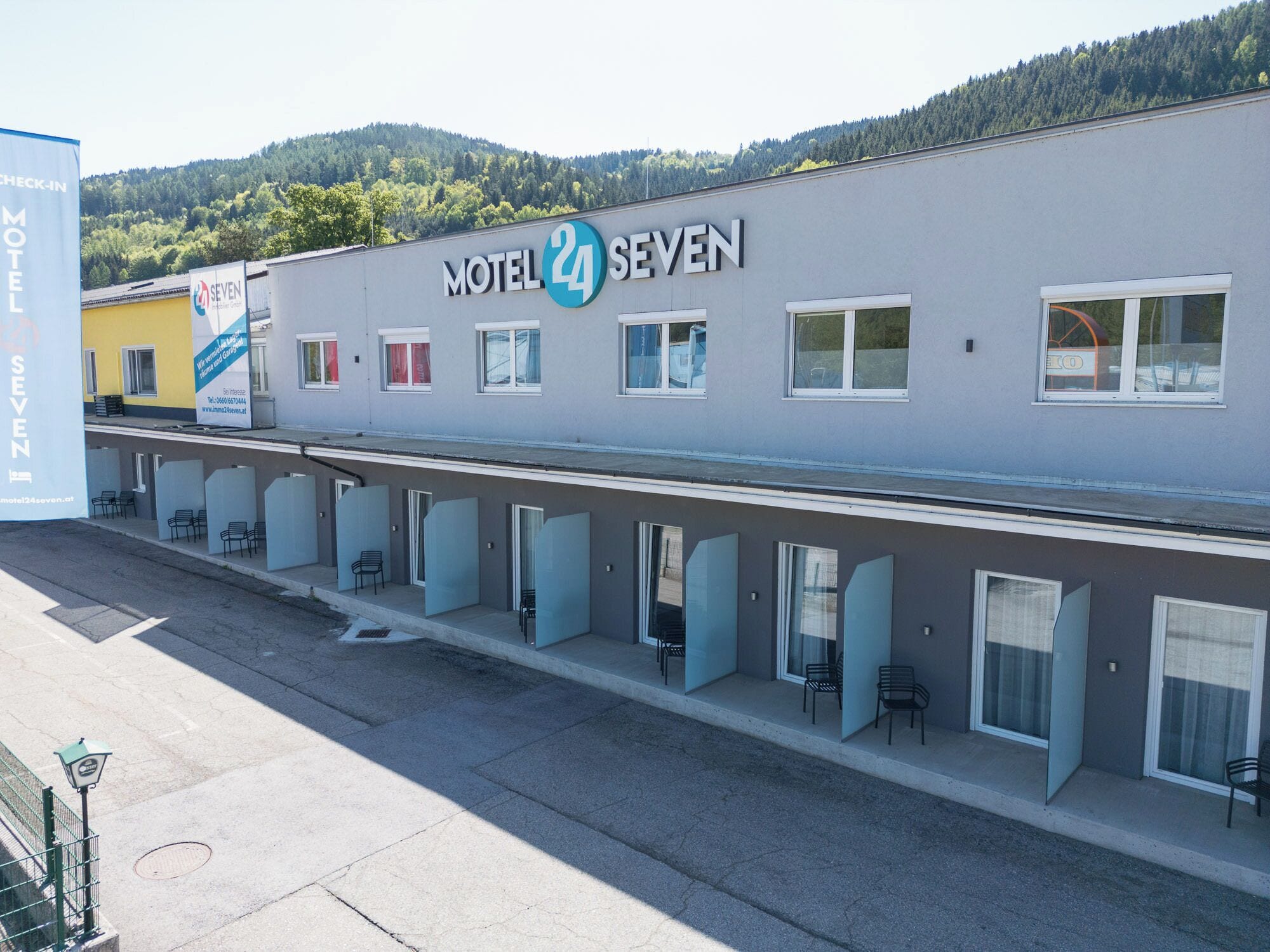 Un motel con un letrero que dice "Motel 24 SEVEN" y un área de recepción con sillas y un letrero de "SEVEN".