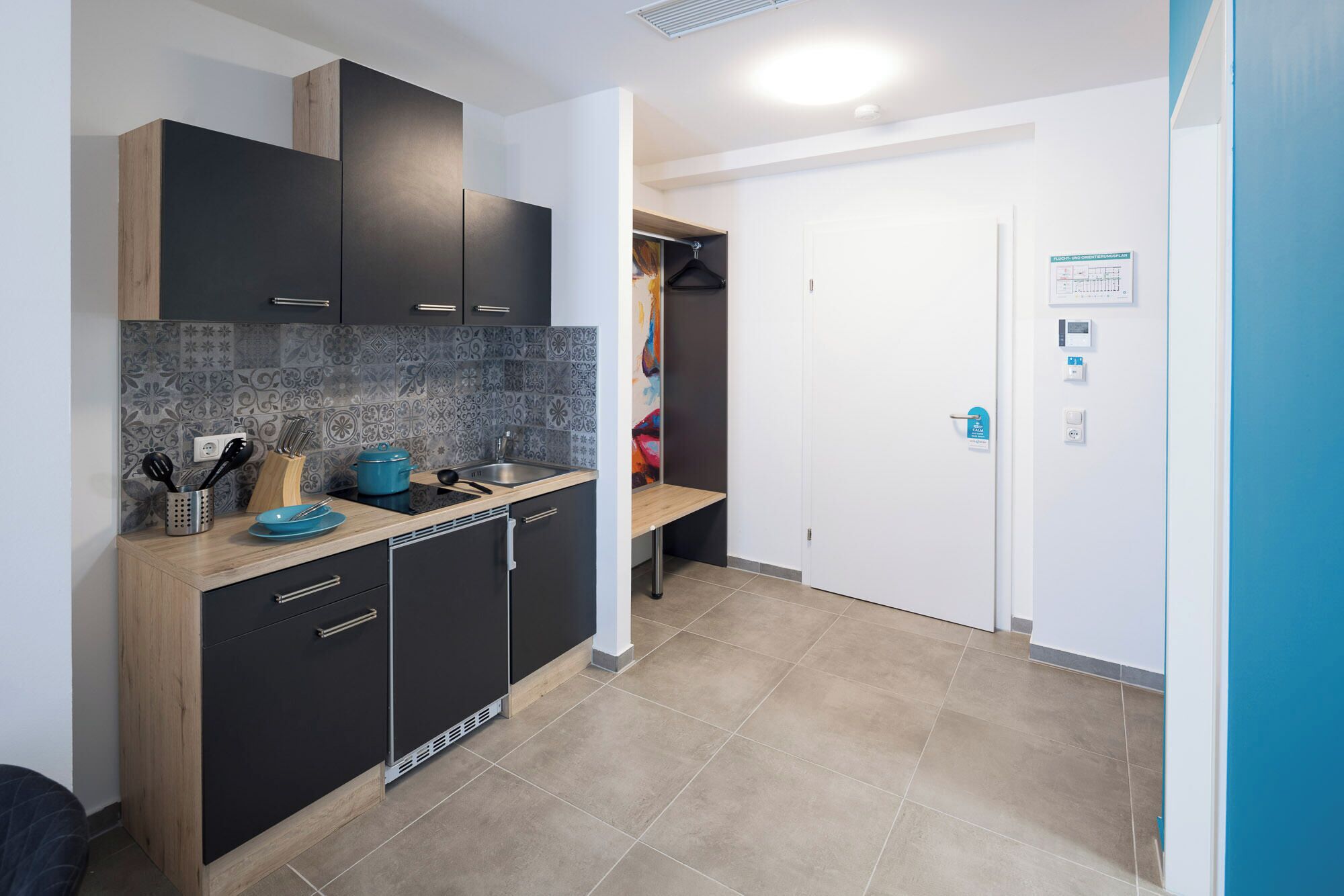 Una cocina moderna con armarios oscuros, encimera de madera y salpicadero de azulejos.