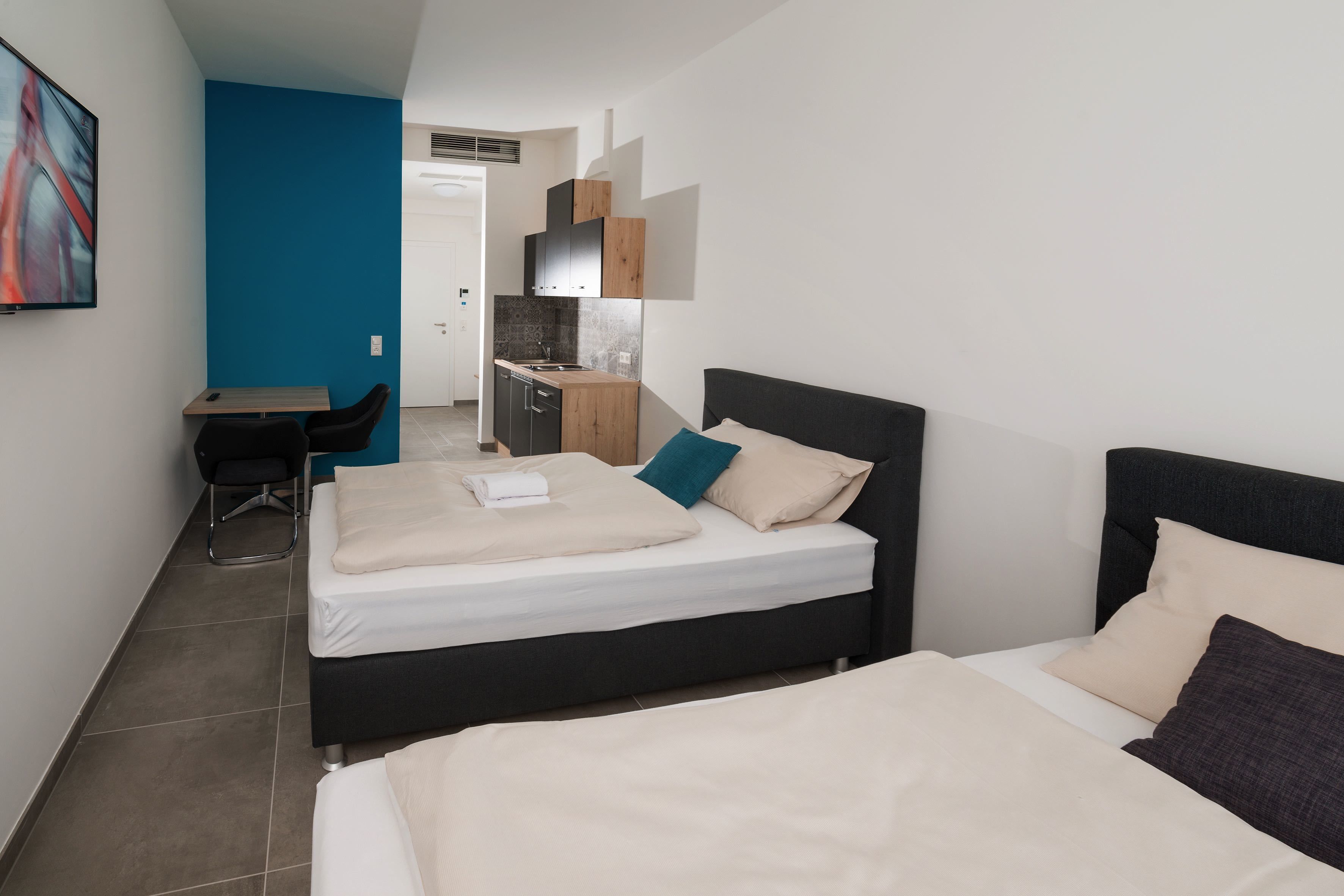 Een moderne hotelkamer met een groot bed, een bureau en een kitchenette.