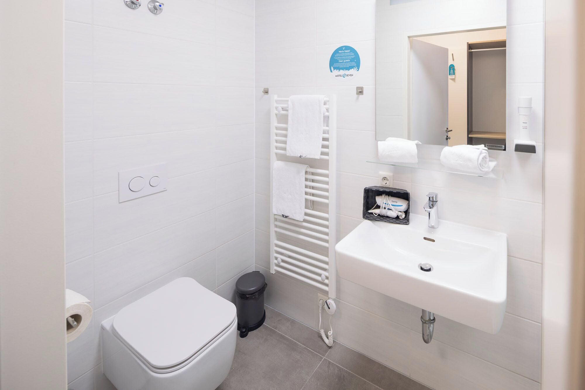 Ein kleines Badezimmer mit Toilette, Waschbecken mit Spiegel und Handtuchhalter.