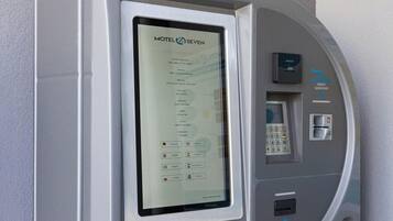 Un quiosco de autoservicio con una pantalla que muestra 'Motel 7 SEVEN' y diversas opciones de pago, incluyendo tarjeta de crédito y tarjeta de habitación.