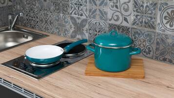 A kitchen with a stove, a pot, and a sink.