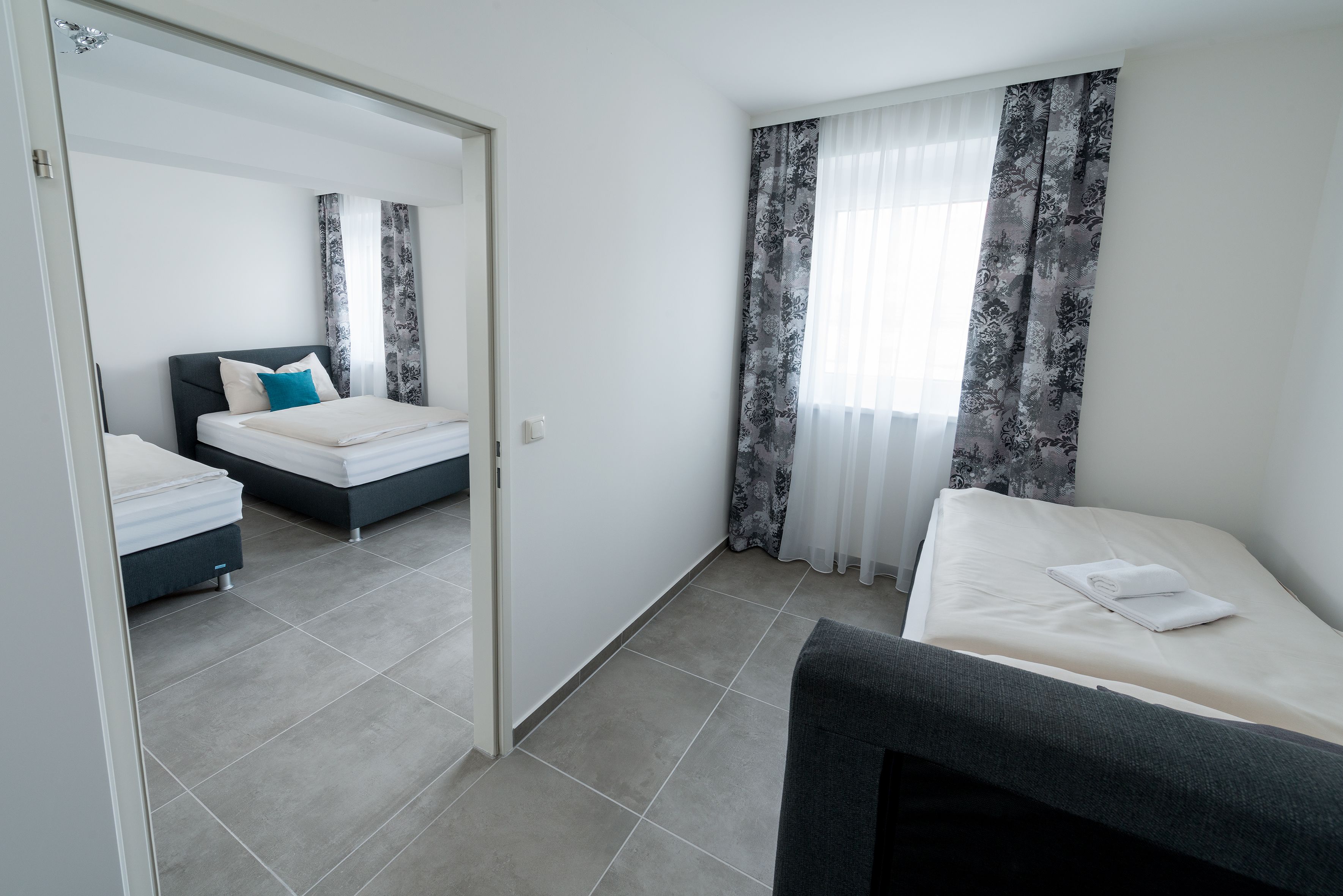A hotel room with two beds, a large mirror, and a view of the street.