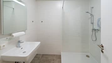 A modern bathroom with a white sink, mirror, and shower.