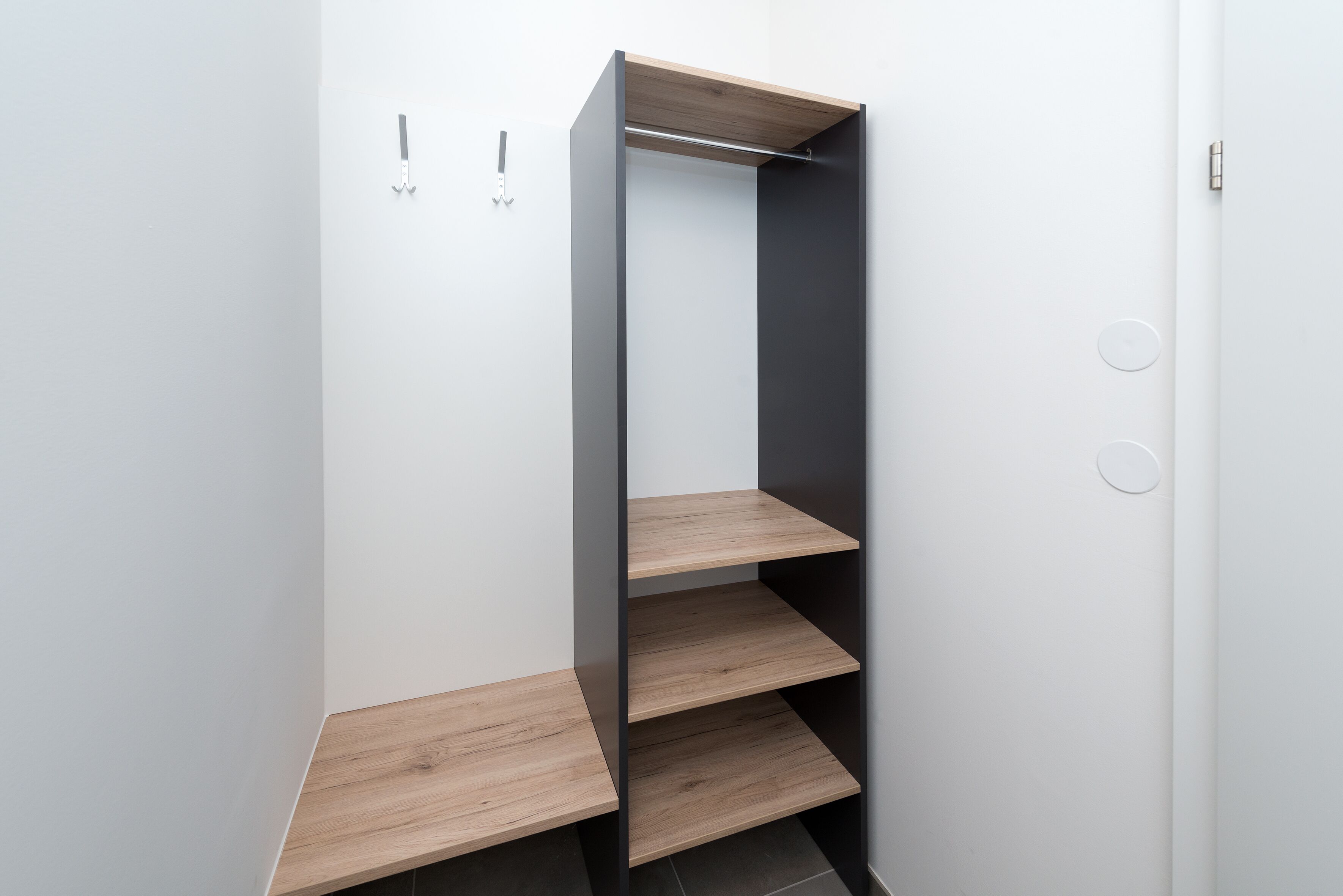A modern, minimalist wardrobe with a wooden finish and a black frame.