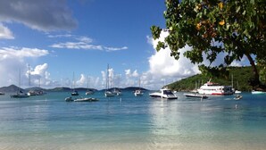 Une plage avec des bateaux et un ferry amarré près du rivage.