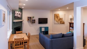 A modern living room with a fireplace, a flat-screen TV, a sofa, and a dining table.