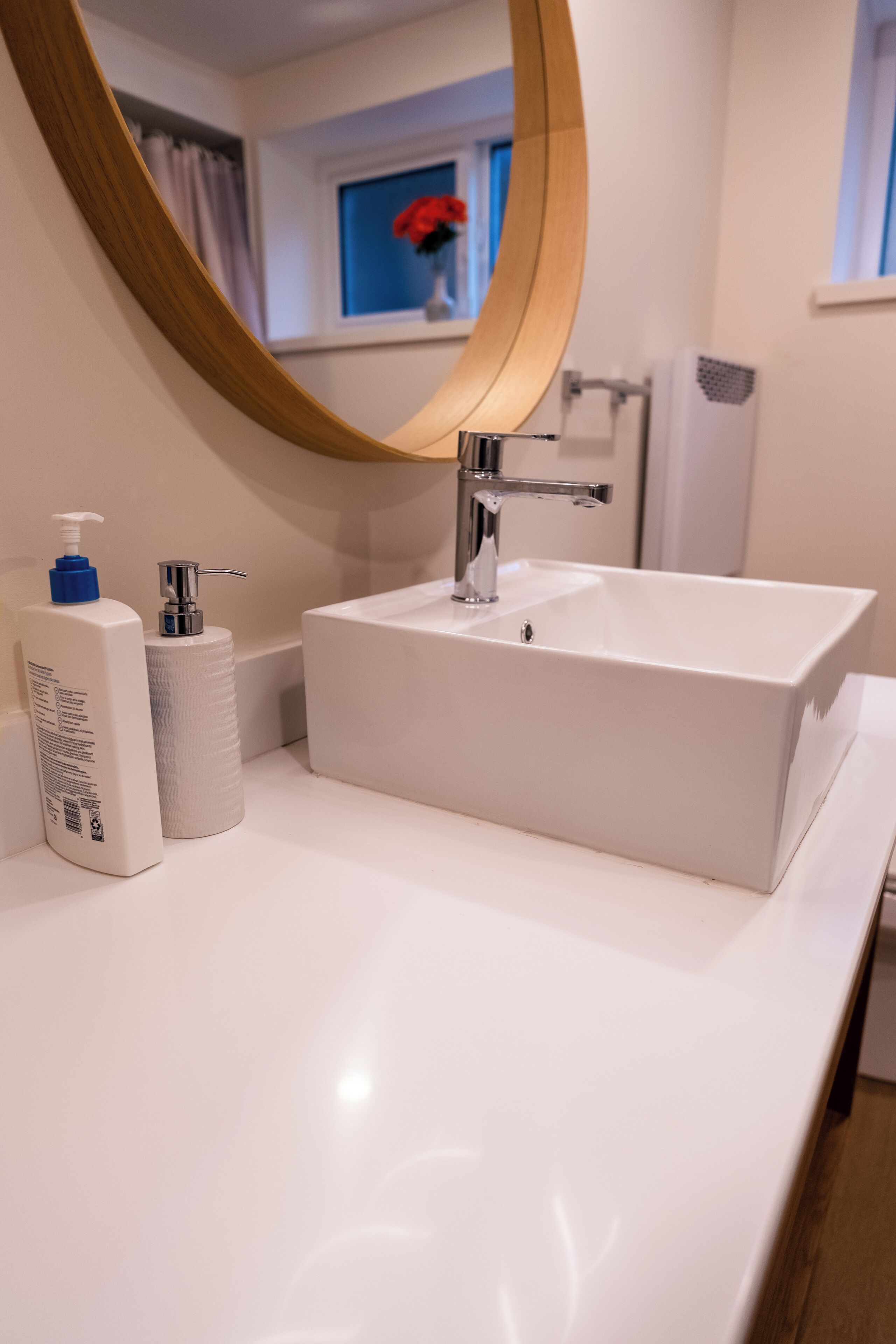 Une salle de bain avec un lavabo blanc, un miroir et des articles de toilette posés sur le comptoir.