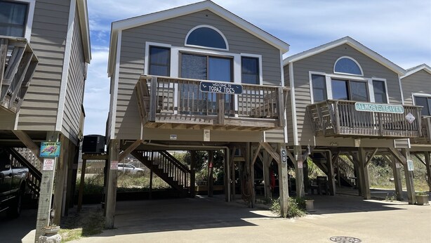 Une rangée de maisons de plage dotées de balcons, chacune portant un nom.