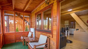 Eine Holzchalet mit einer gemütlichen Sitzecke, einer Küche und Blick auf die umliegende Landschaft.
