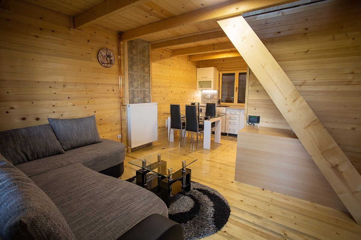 A cozy wooden interior with a sofa, a dining table, and a kitchen area.