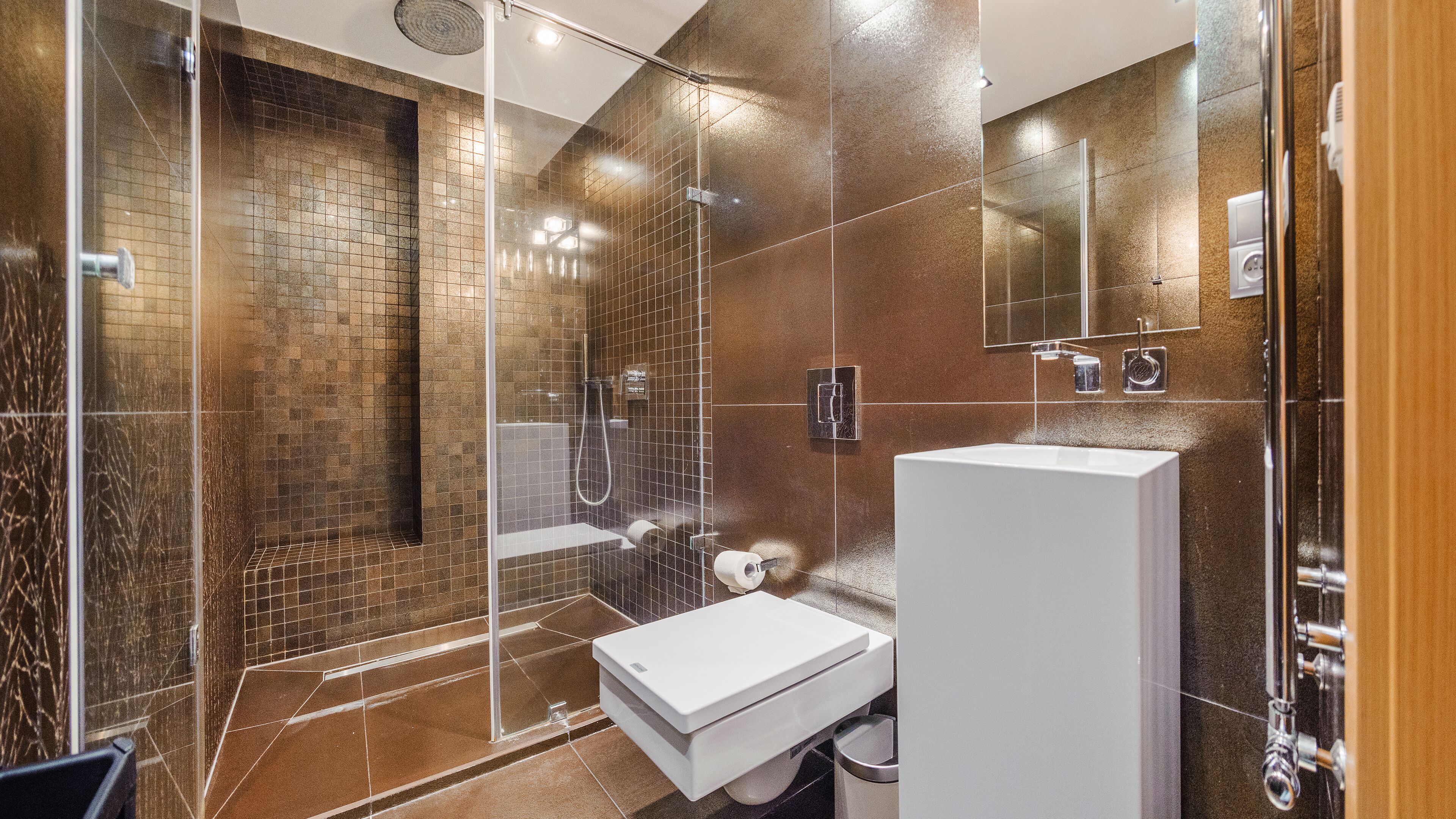 A modern bathroom with a glass-enclosed shower, a white sink, and a large mirror.