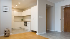 A modern kitchen with white cabinets, a built-in oven, and a wooden floor. - Apartamenty Sun&Snow Wczasowa Południowe (Ustka)
