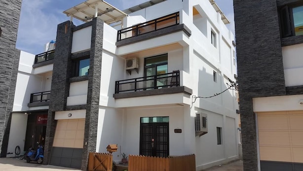 A multi-story residential building with balconies, a garage, and a small outdoor seating area. - Fishmoon Homestay (Magong)