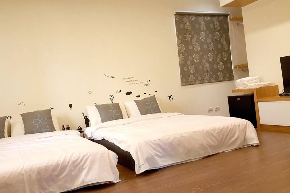 A hotel room with two beds, a TV, a desk, and a wardrobe.