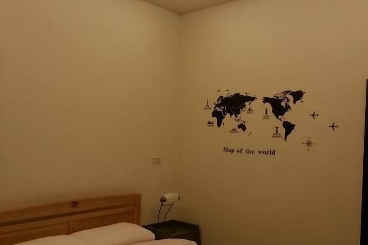 A bedroom with a bed, a nightstand, and a wall map labeled "Map of the world".