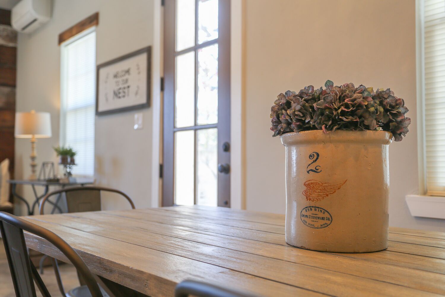 A rustic wooden table with a potted plant in a vintage-style pot.